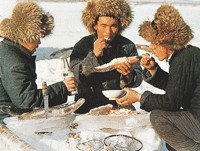 冬季在捕鱼现场吃鲜鱼的赫哲族男子
